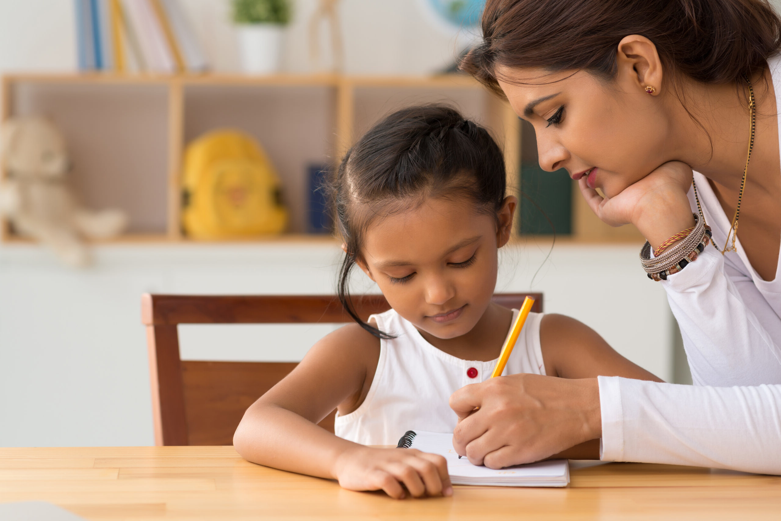 Woman helping young girl with homework