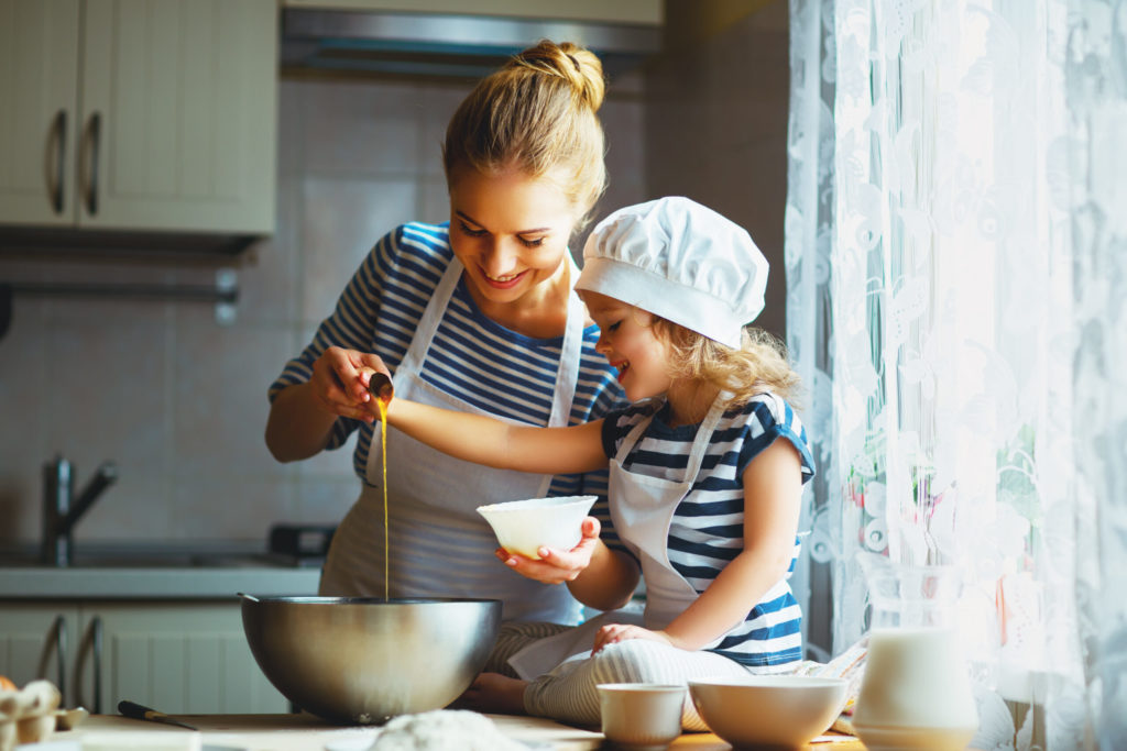 Adult and young girl baking together in kitchen